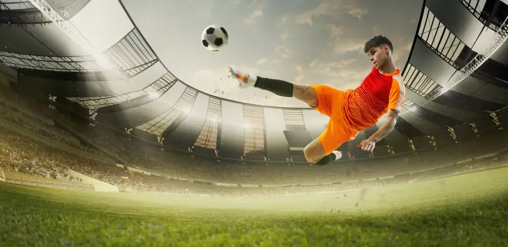 Fussball Spieler im orangenen Triko im Stadion schießt Ball